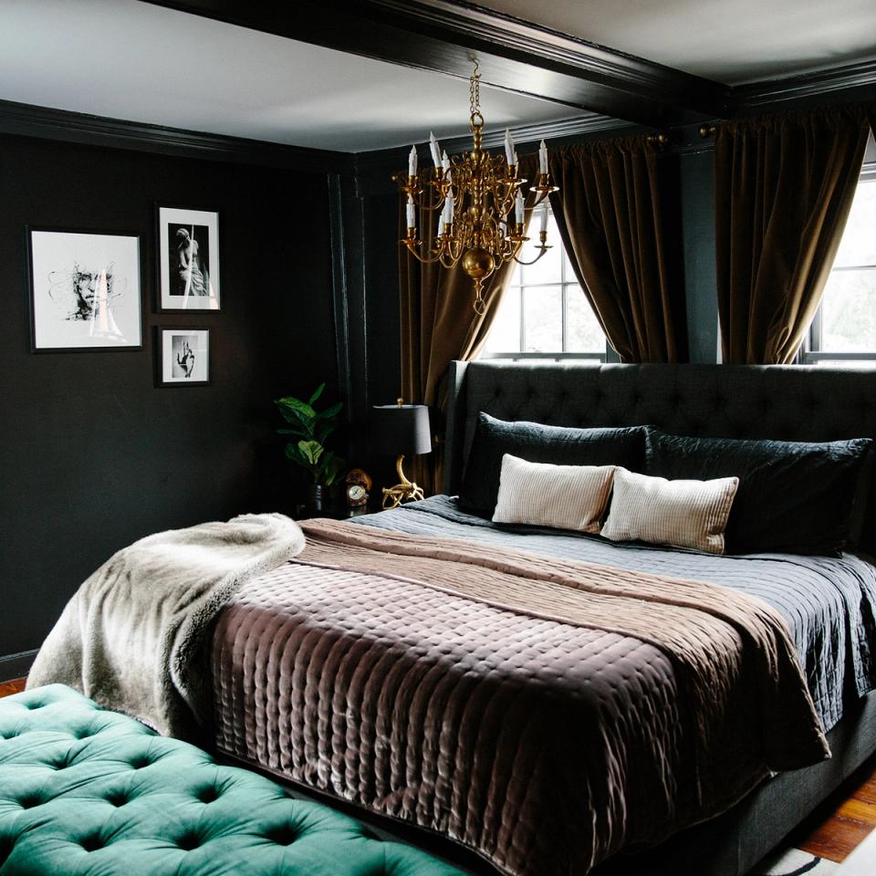 Dramatic dark bedroom with gold chandelier, jewel tones, and luxe layered bedding.