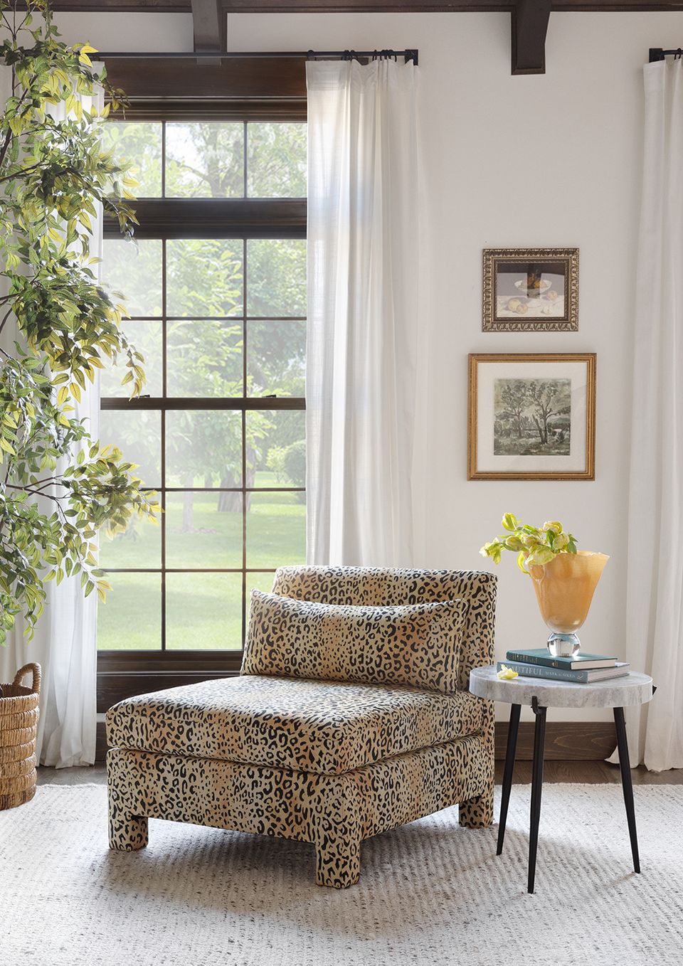 Farmhouse seating area with leopard print chair, exposed beams, and framed botanical art