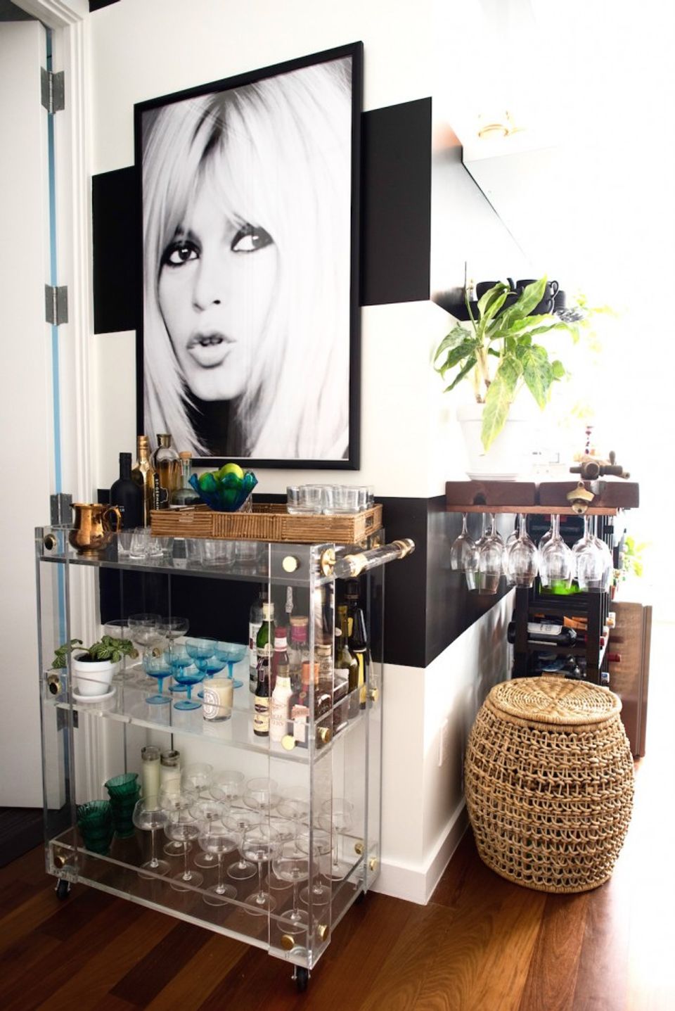 Eclectic entryway blending black and white portraiture with brass accents and woven natural textures