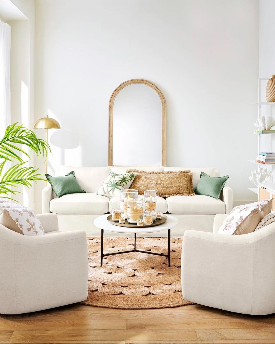 Organic modern living room with curved cream furniture, natural fibers, sage accents, and arched mirror