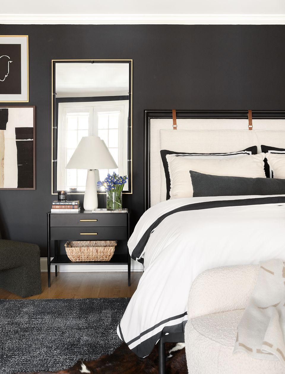 Modern moody bedroom featuring charcoal walls, cream bedding, and brass-trimmed window frame
