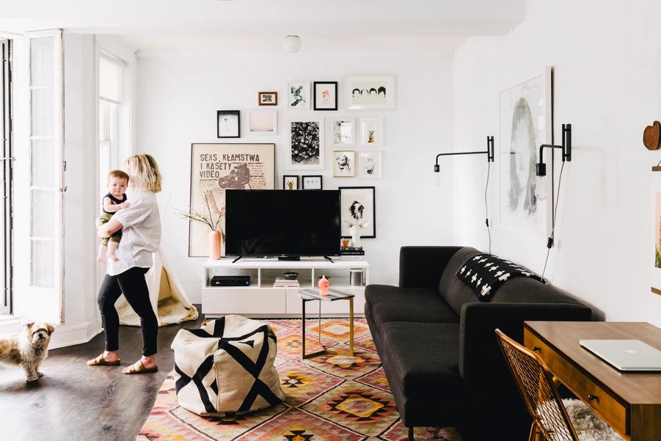 Eclectic gallery wall styled living room with black media console and colorful area rug