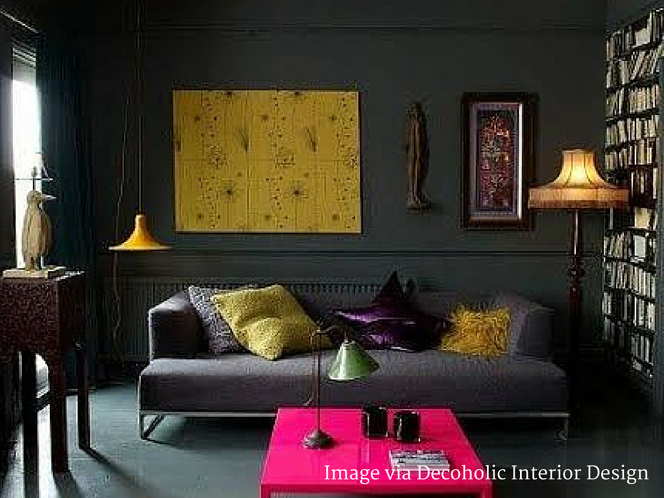 Dark moody lounge with neon pink accent table and mustard-yellow art