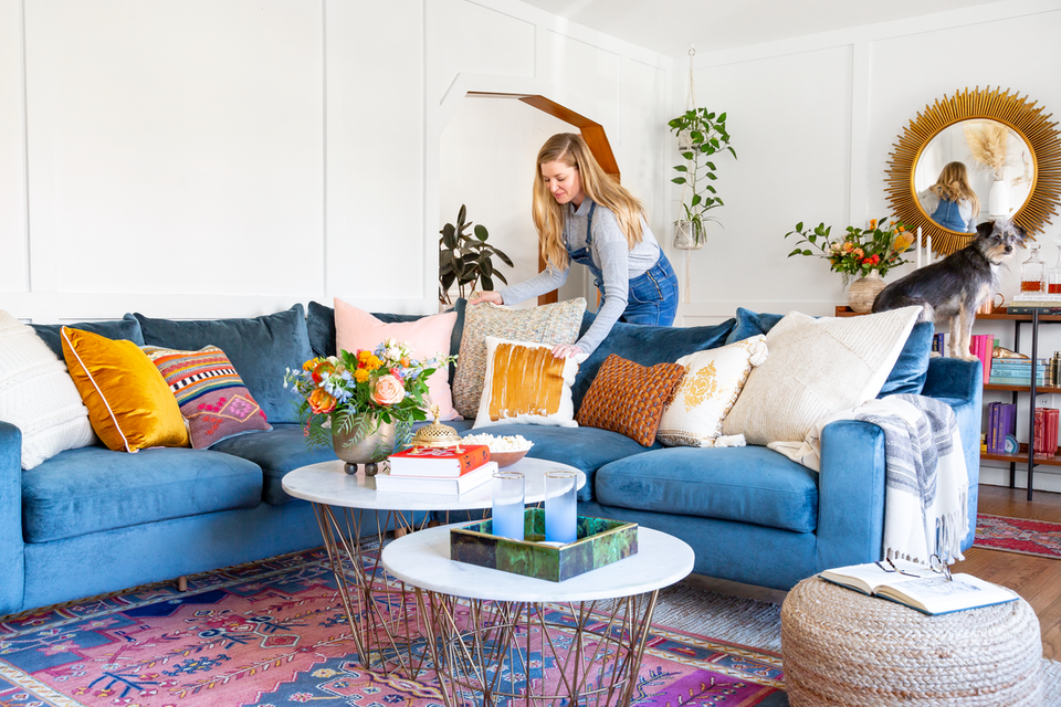 Eclectic bohemian living room with cobalt sectional, layered textiles, vibrant patterned rug, and botanical accents