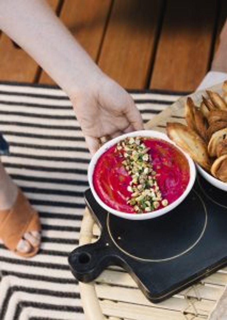 Minimalist coastal dining with vibrant beet bowl, striped runner, and warm wood tones