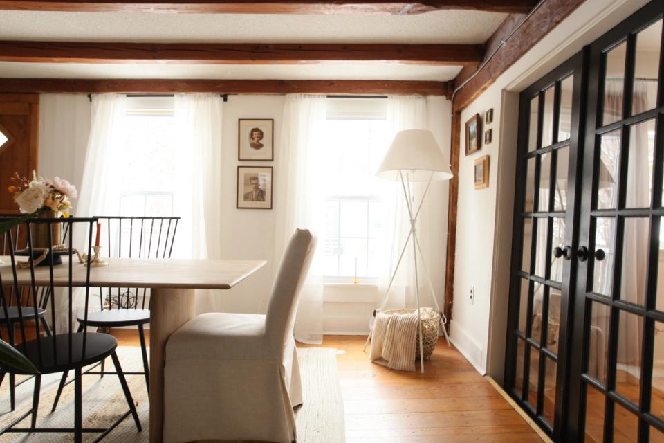 Transitional dining area with dark French doors, cream upholstered chair, and warm wood accents