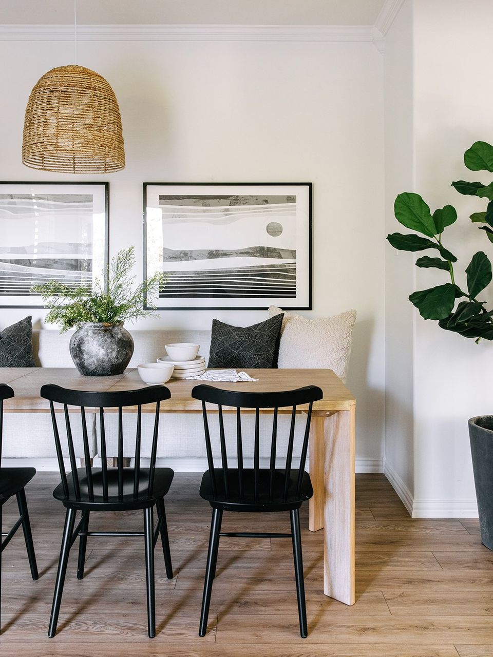 Scandinavian dining nook with white walls, natural wood, and modern black chairs