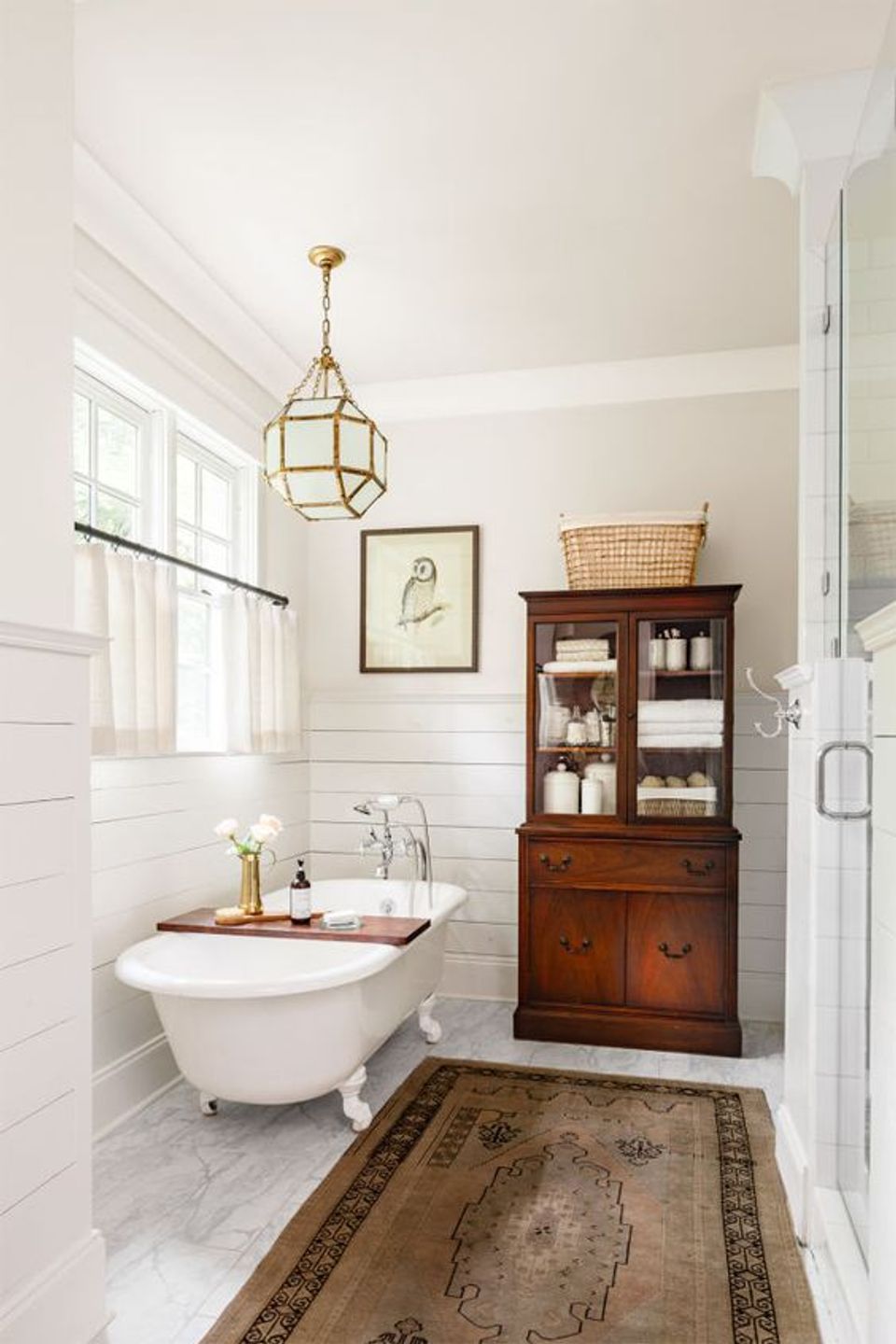 Classic vintage bathroom featuring white subway tile, brass pendant, wooden vanity, and traditional patterned runner