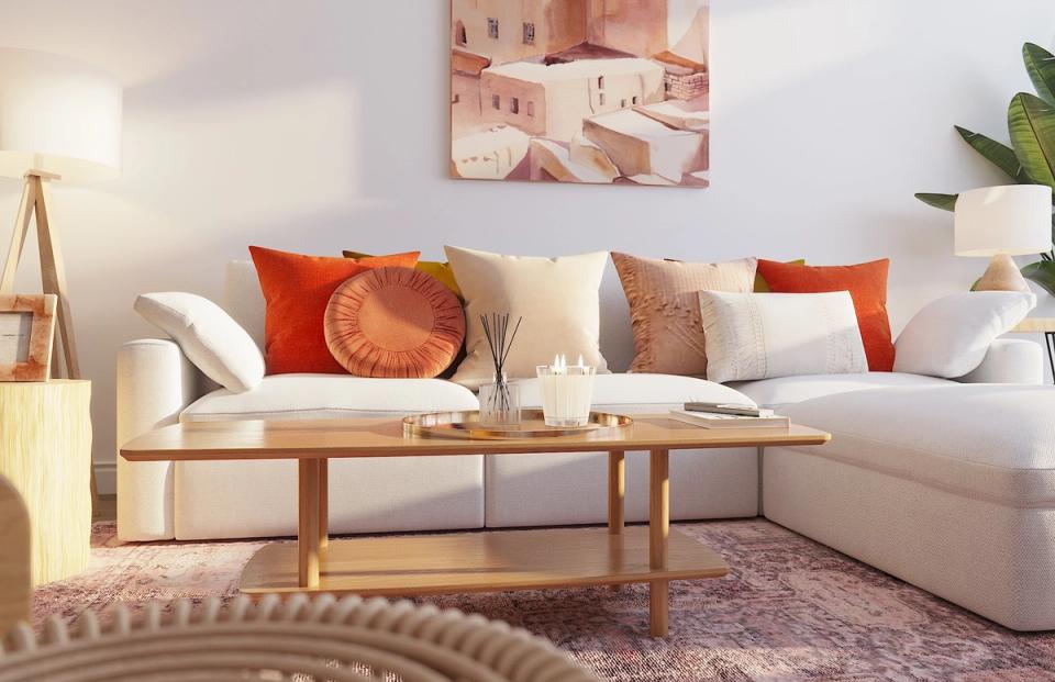 Warm minimalist living room with cream sectional, terracotta accents, natural wood table, and soft neutral palette
