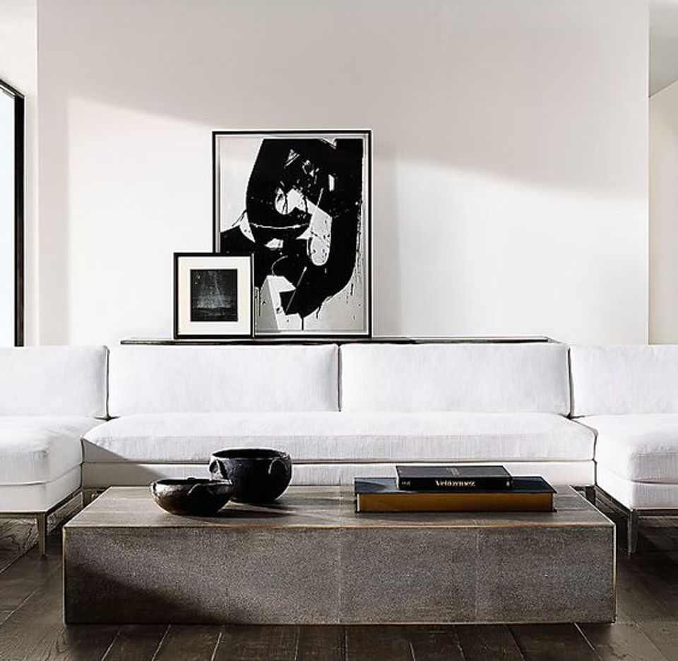 Minimalist living room with white sectional, shagreen coffee table, and black abstract art