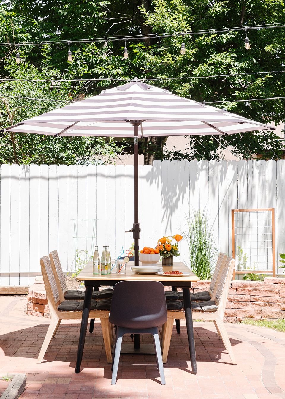 Minimalist modern patio with striped umbrella and sculptural wooden dining chairs