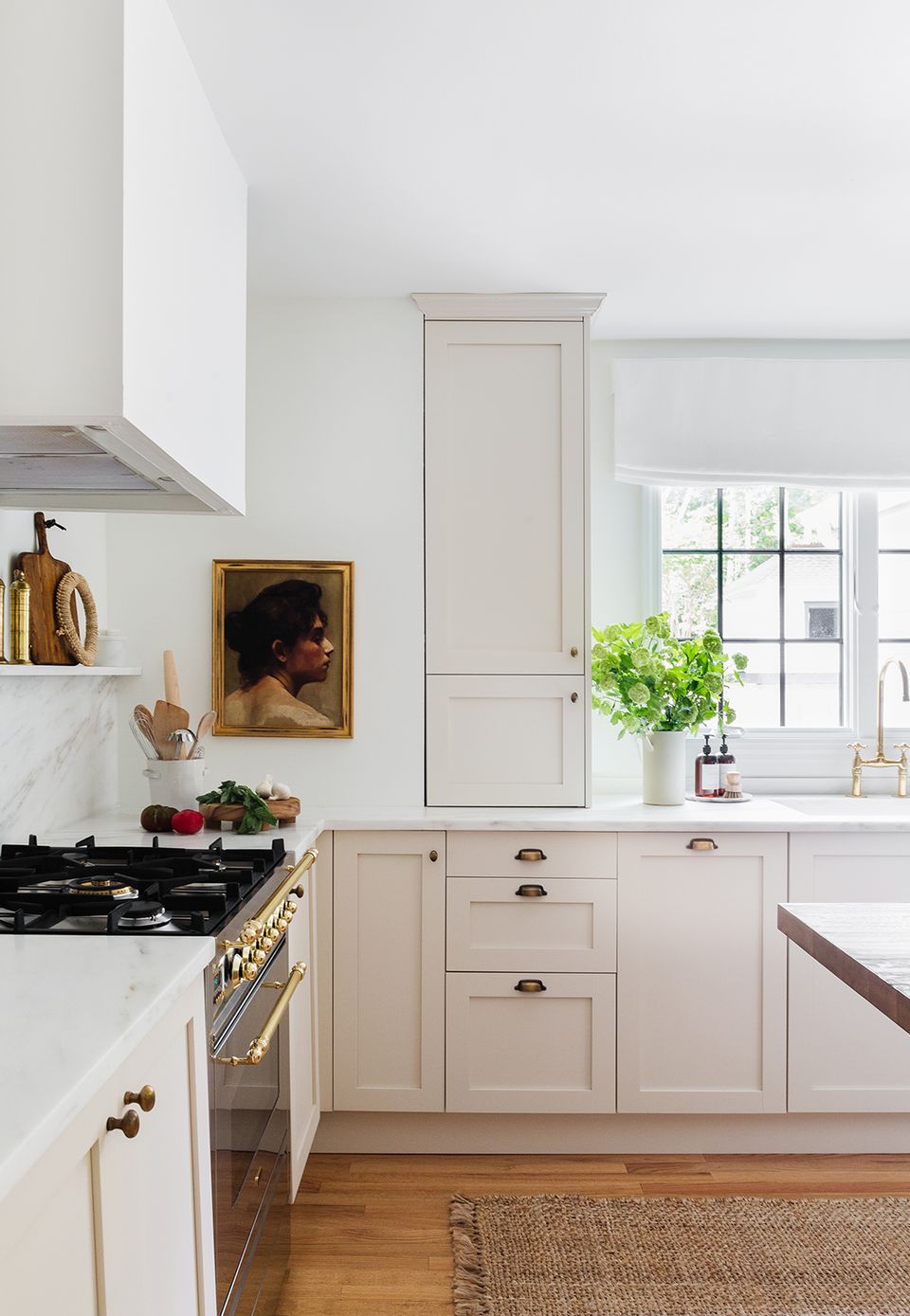 Elegant minimalist kitchen with cream cabinetry, marble counters, and brass hardware