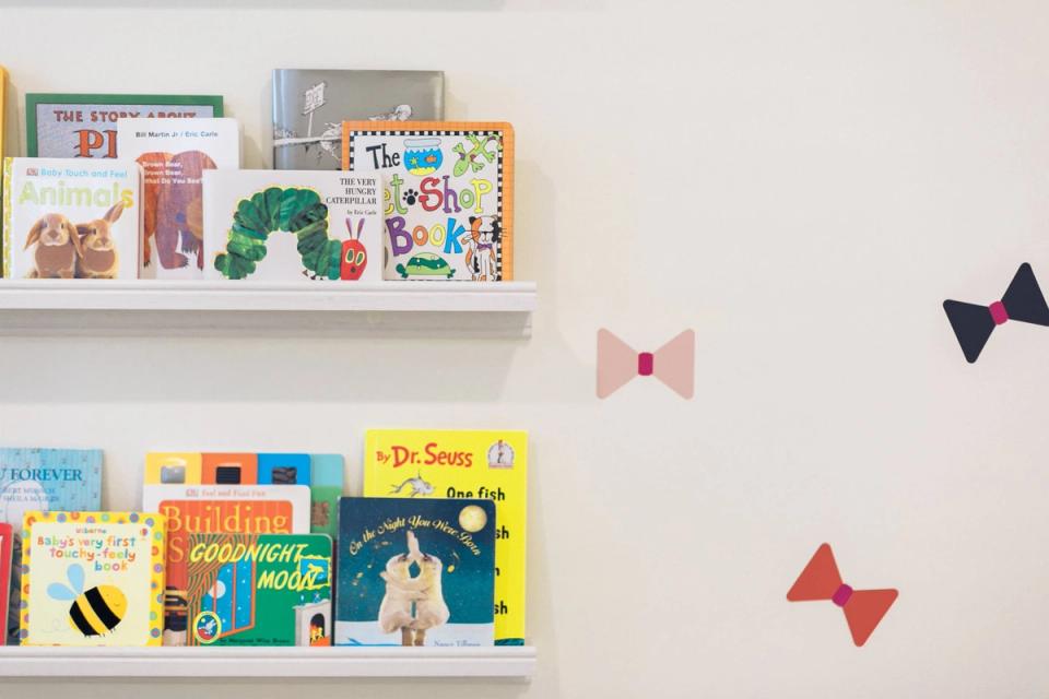 Bright nursery shelving with children's books and colorful fabric bows against soft neutral walls
