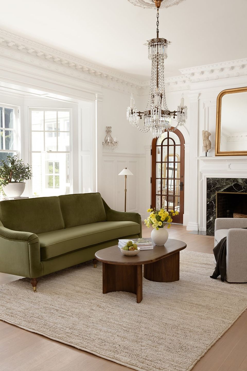 Elegant traditional living room with olive green sofa, crystal chandelier, and refined classical architectural details