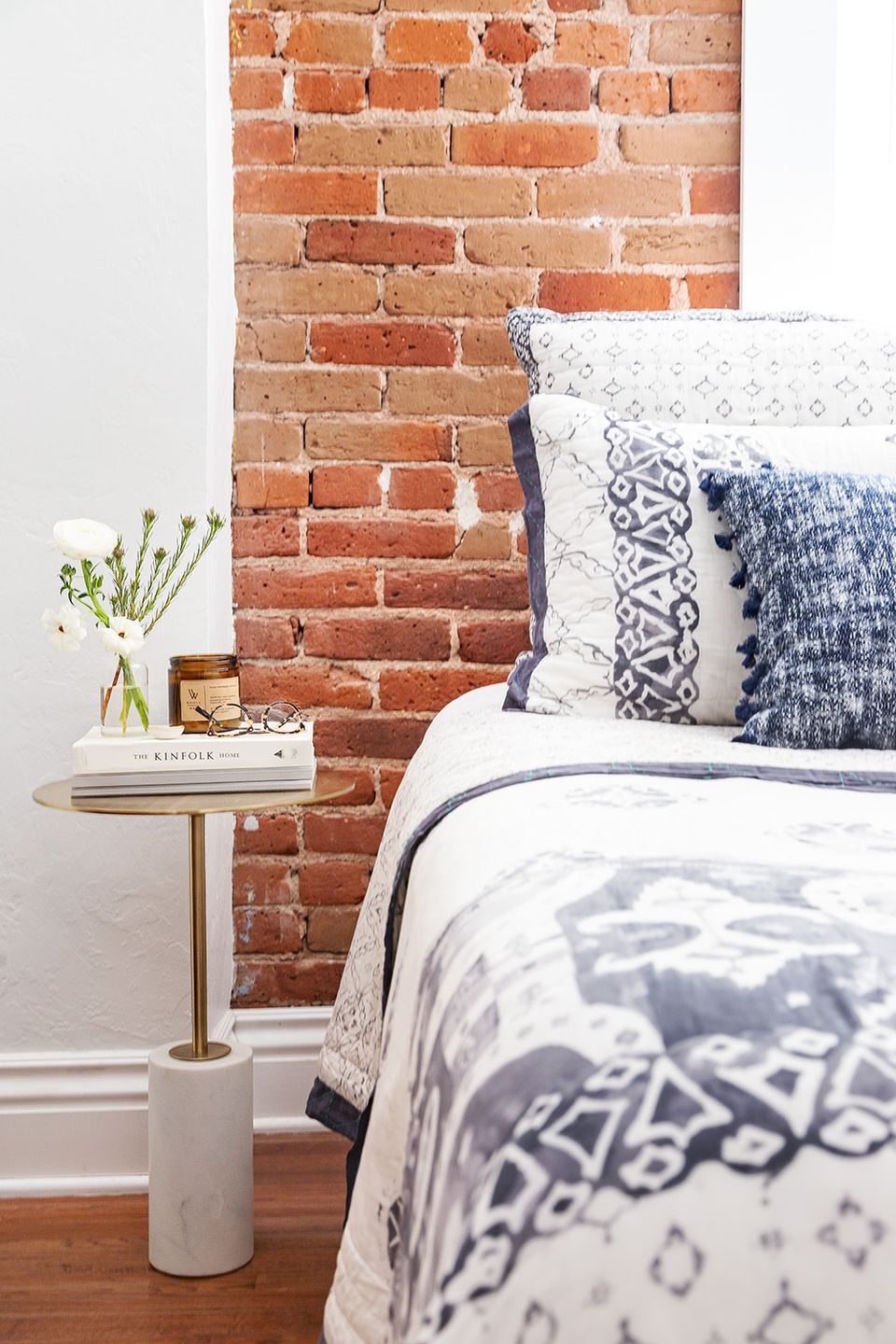Industrial-modern bedroom with exposed brick wall and navy patterned pillows