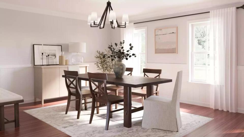 Warm minimalist dining room with natural wood table, dark cross-back chairs, and soft neutral palette