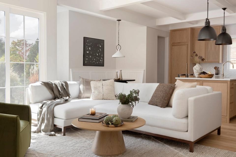 Warm contemporary living-dining combo with cream sectional, natural wood accents, olive green accent chair, and soft neutral palette