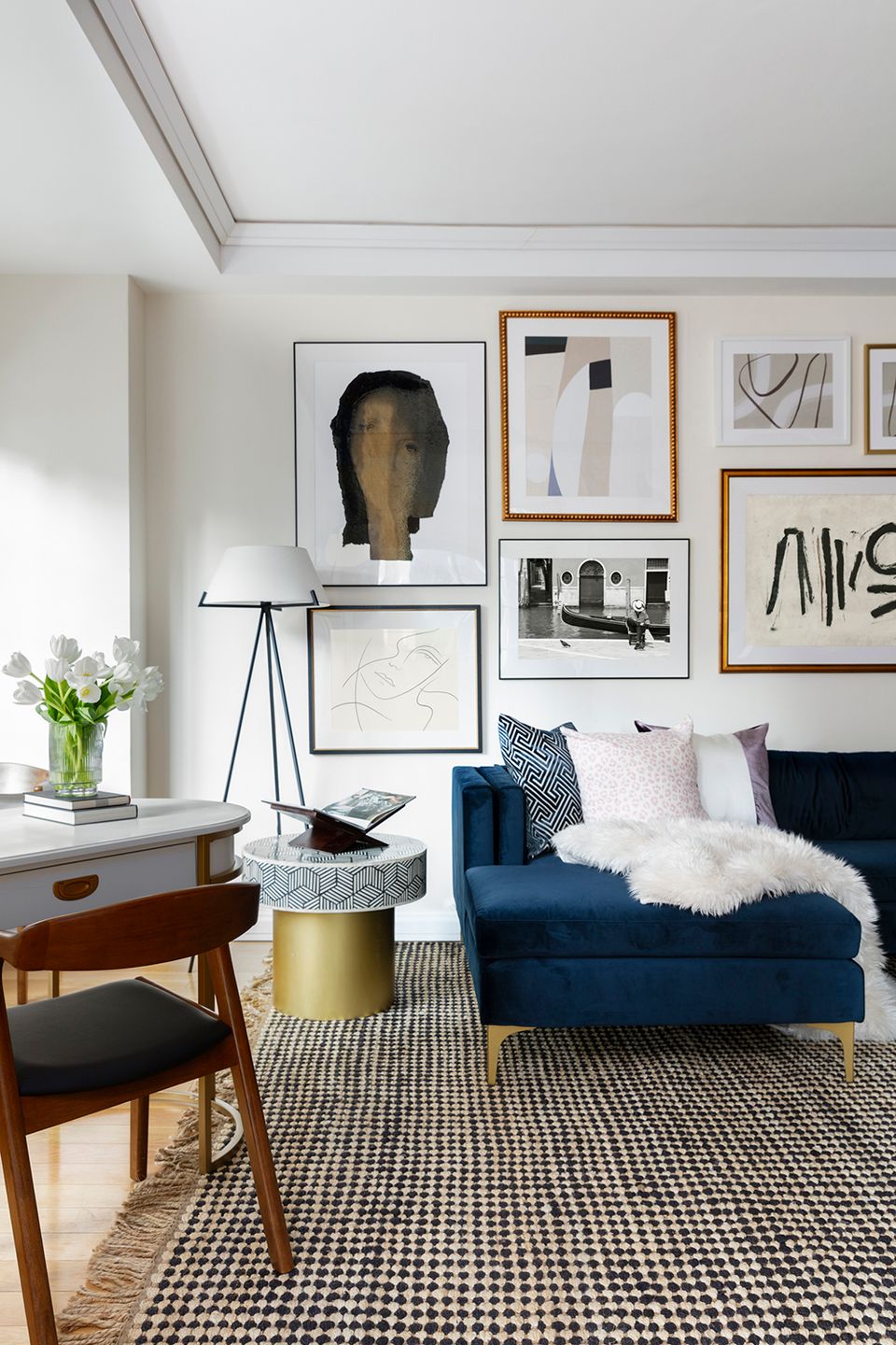 Contemporary space with navy sofa, mid-century desk, geometric rug, and curated gallery wall