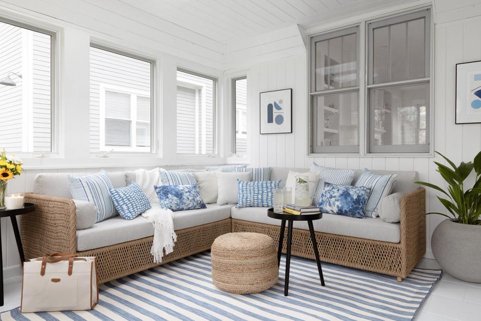 Relaxed coastal seating area with blue striped pillows, natural wicker, and breezy white interior