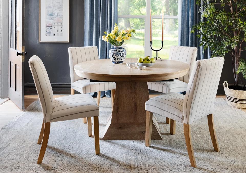 Transitional dining room with cream striped chairs, round wood table, and serene blue-gray palette