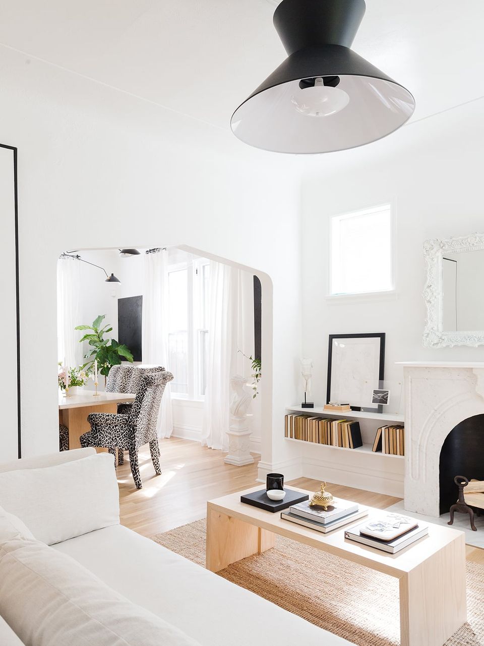 Scandinavian minimalist living room with natural wood accents, black pendant light, and bright white palette creating an airy, serene atmosphere.