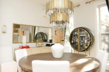 Luxe modern bar cabinet display with gold chandelier, round mirrors, and neutral palette creating sophisticated entertaining space