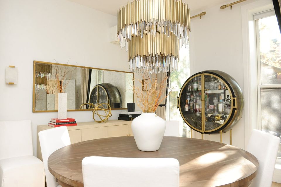 Luxe modern bar cabinet display with gold chandelier, round mirrors, and neutral palette creating sophisticated entertaining space