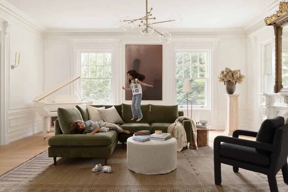 Bright transitional living room with olive-green performance sofa, cream accents, and natural light