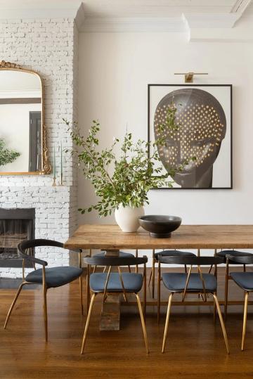 Modern dining space with white brick fireplace, natural wood table, and contemporary black chairs