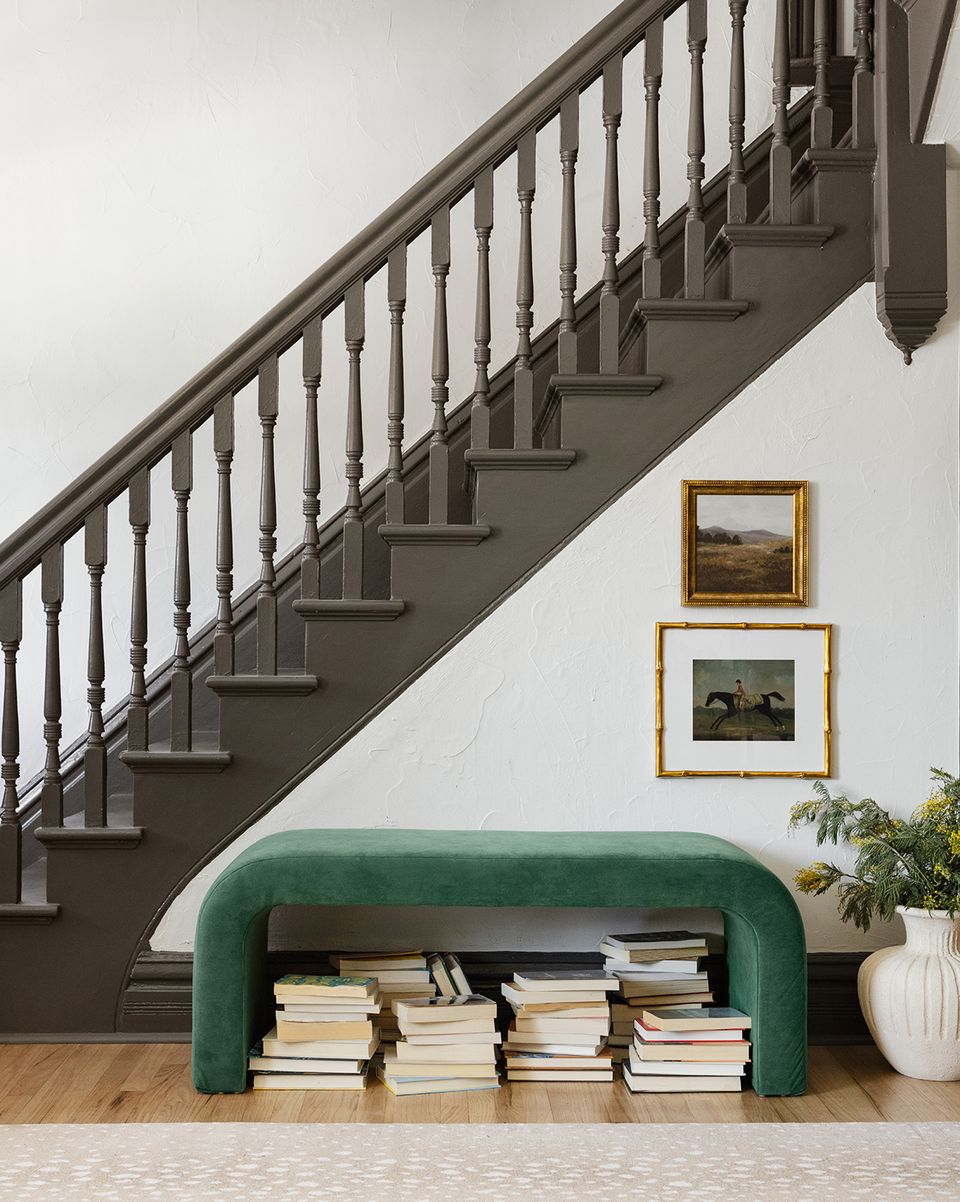 Modern staircase with emerald green curved bench below, gallery-style framed artwork, minimalist sophisticated vibe