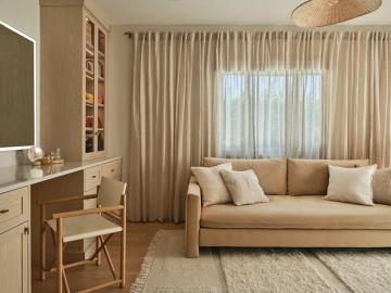 Warm, neutral living room with caramel sofa, cream curtains, natural wood accents, and soft taupe walls creating a sophisticated, airy mood.