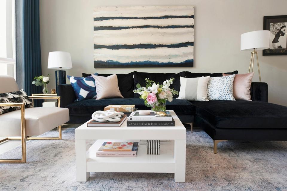 Sophisticated black sectional with cream accents, striped wall art, and monochromatic color scheme