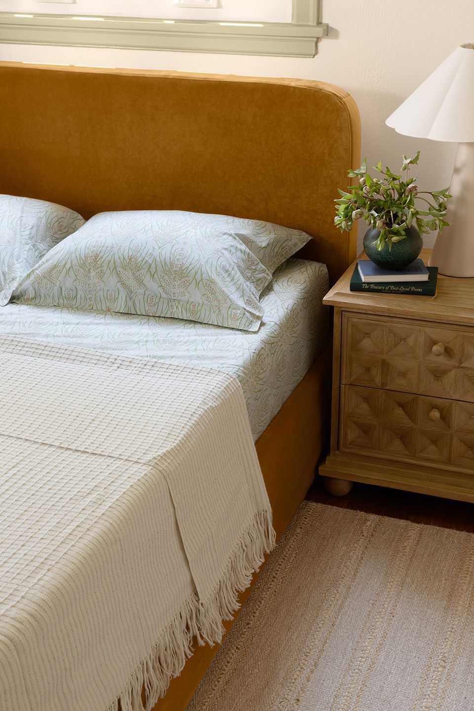 Minimalist boho with mustard upholstered headboard, natural wood nightstand, and cream bedding
