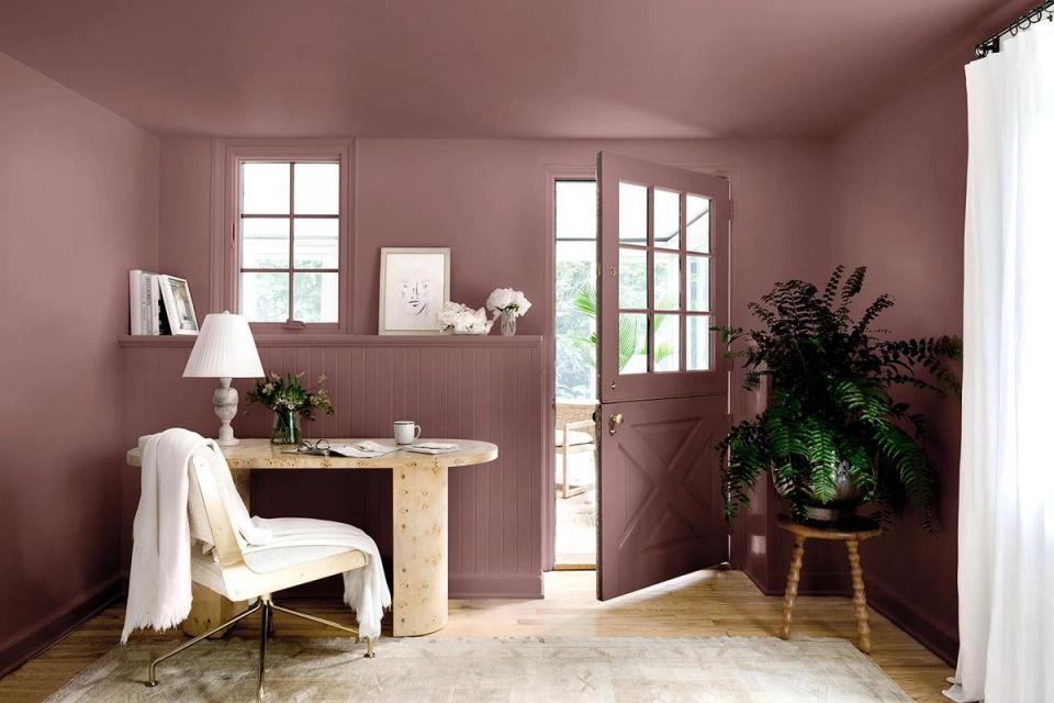 Serene mauve home office with soft walls, natural wood desk, potted plants, and minimalist botanical décor creating calming, contemporary mood.