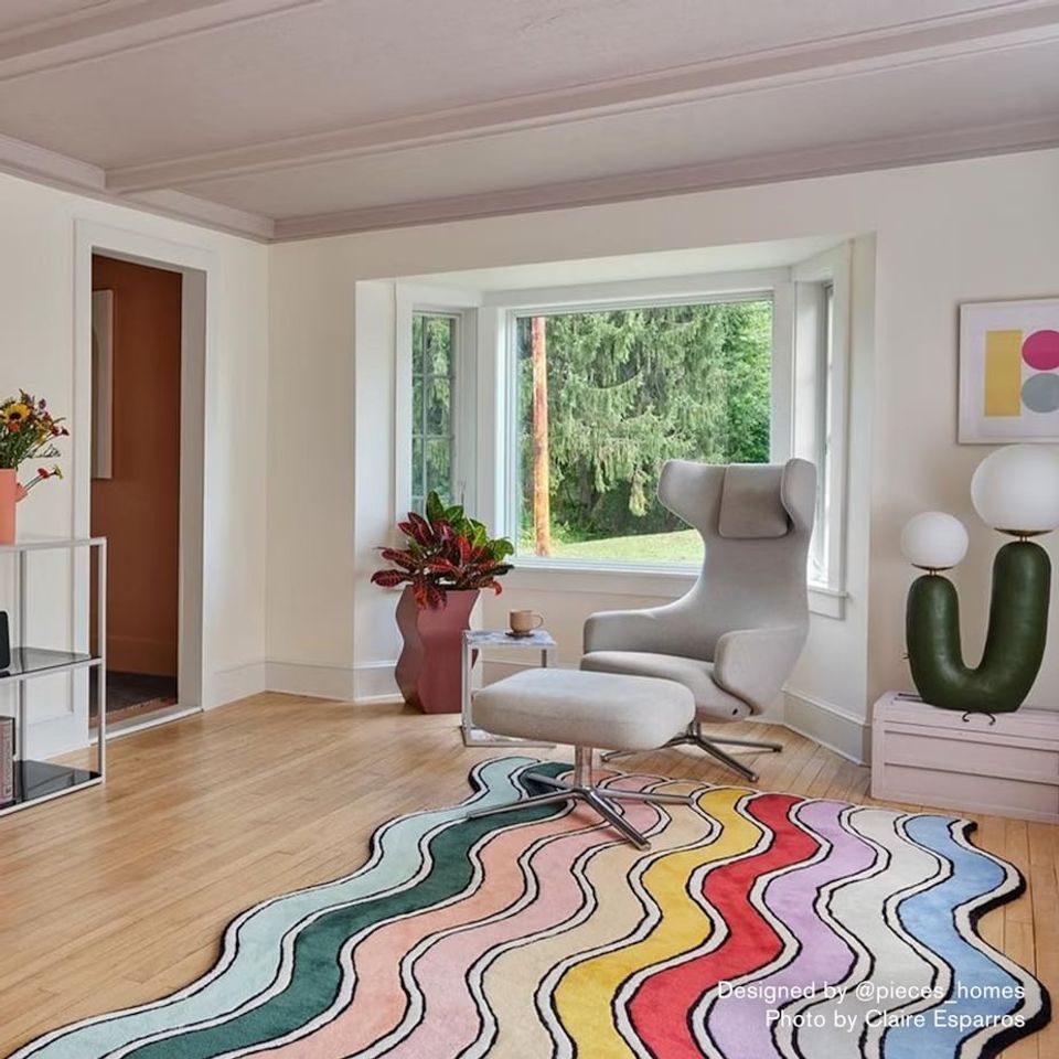 Bright mauve-toned room with colorful wavy area rug, contemporary gray armchair, and natural light creating playful yet refined space