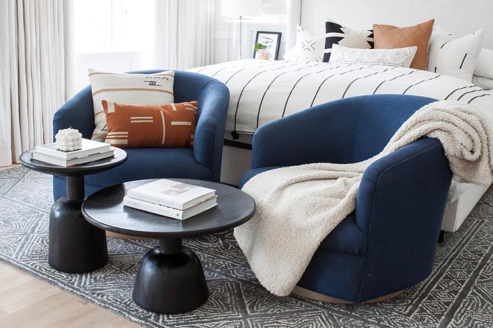 Contemporary bedroom with navy curved furniture, cognac leather pillows, and neutral striped bedding