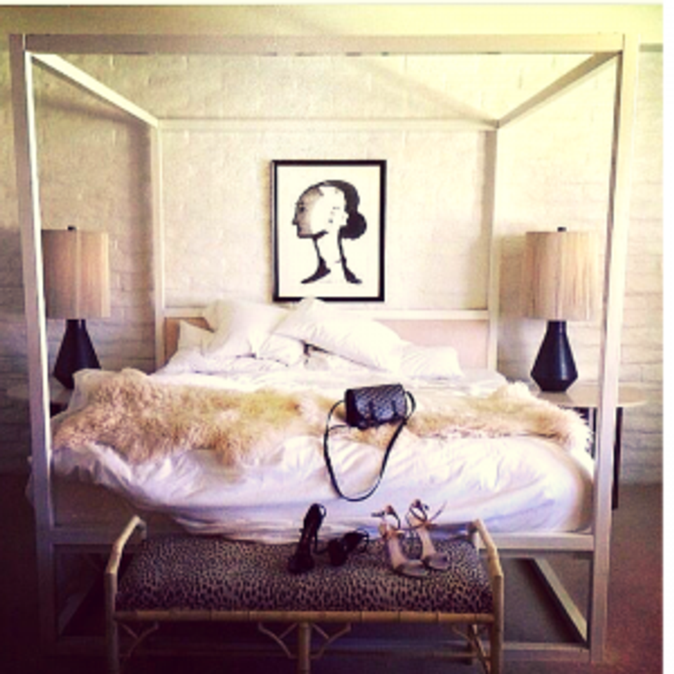 Scandinavian bedroom featuring cream sheepskin throw draped over canopy bed with warm minimalist styling