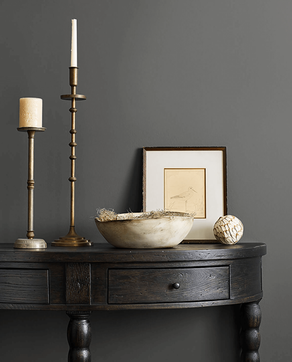 Sophisticated console styling with dark gray wall, brass candlesticks, and neutral accessories in refined moody palette