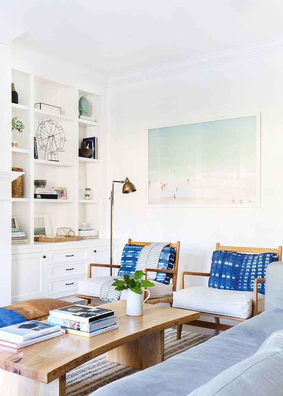 Bright East Coast coastal living room with crisp white shelving, natural wood furniture, and blue patterned accents