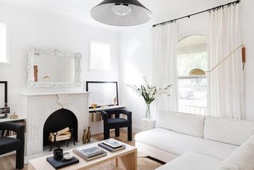 Minimalist Parisian living room blending black fireplace, white sofa, and natural wood accents