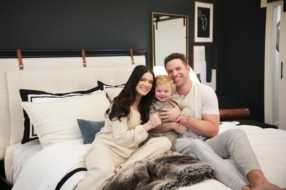 Cozy contemporary bedroom with dark walls, cream bedding, and warm family moment captured