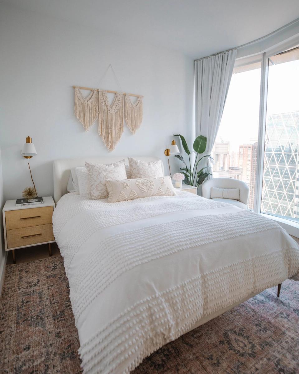 Bright boho bedroom with macramé wall hanging, wood nightstand, and airy neutral palette