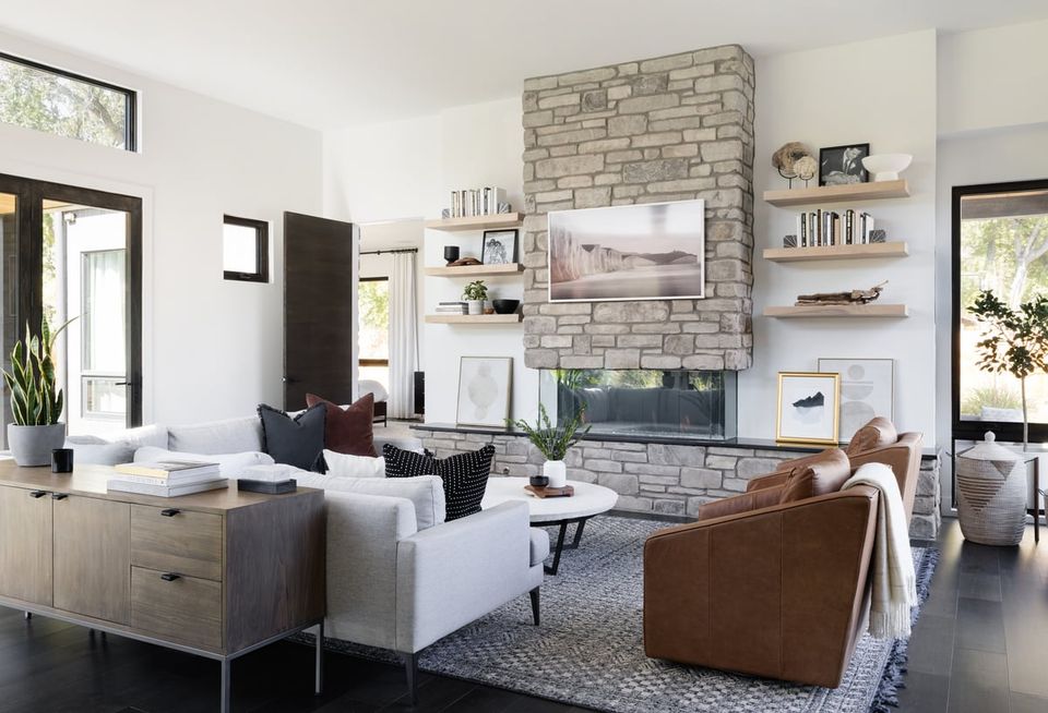 Modern living room with exposed brick fireplace, neutral palette, and mixed seating in sleek contemporary style
