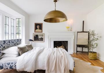 Bright contemporary bedroom featuring brass pendant, fireplace focal wall, and gallery wall arrangement