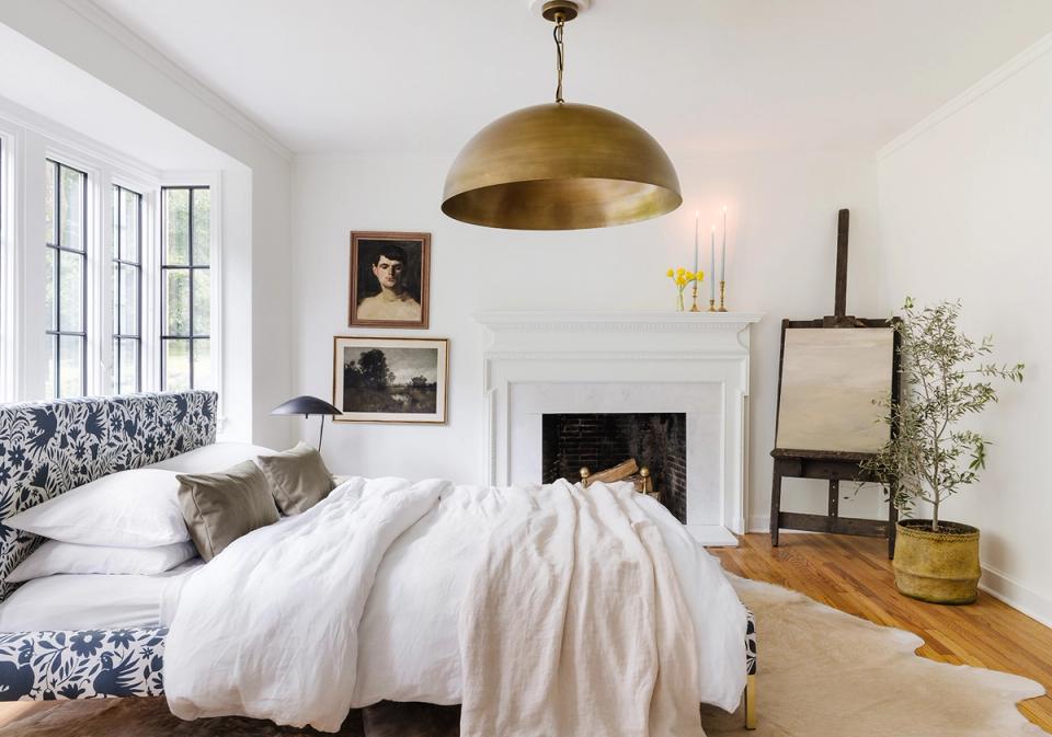 Bright contemporary bedroom featuring brass pendant, fireplace focal wall, and gallery wall arrangement