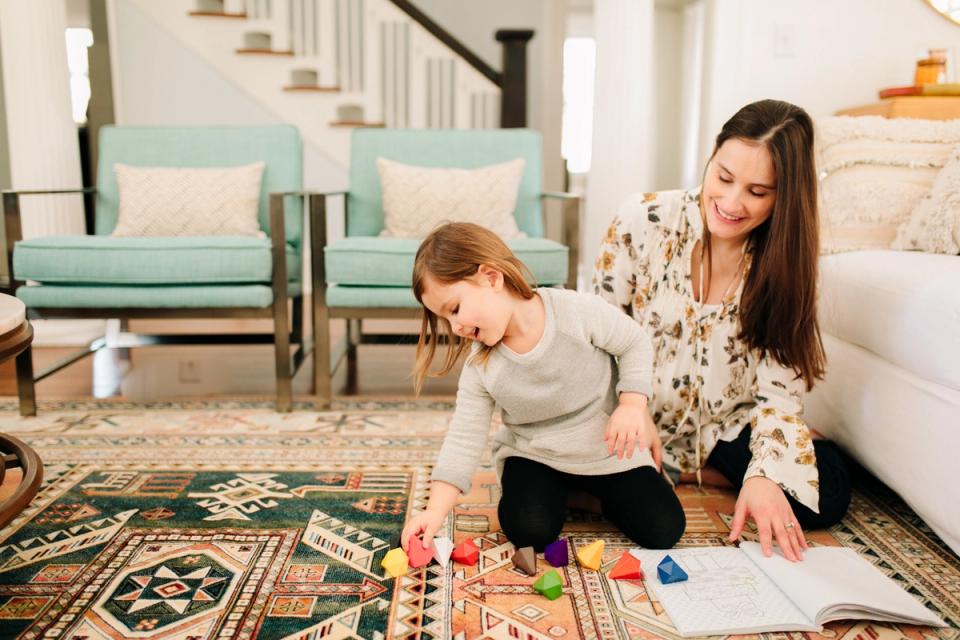 Bright, airy homeschool space with mid-century mint armchairs, geometric patterned rug, and warm neutral tones creating an inviting learning environment.