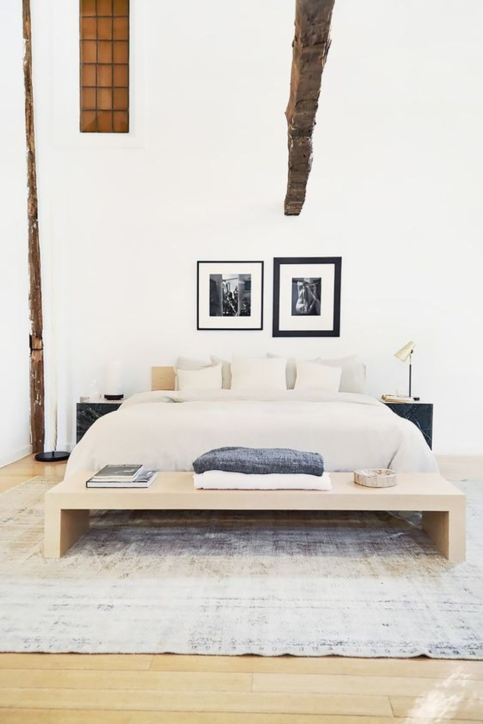 Minimalist bedroom with crisp whites, natural wood, and organic branches creating serene, uncluttered aesthetic