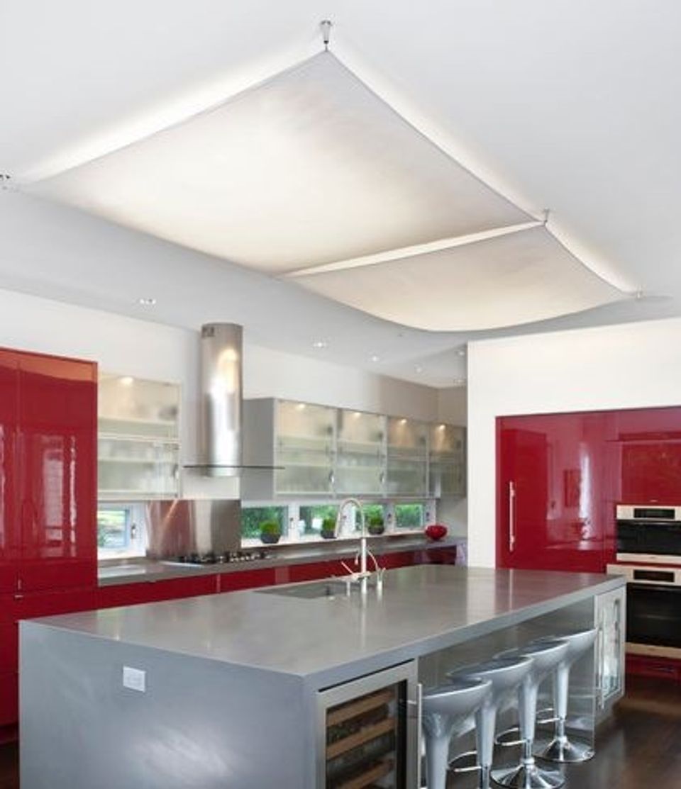 Modern kitchen with sleek white recessed panel lighting and bold red cabinetry creating contemporary elegance