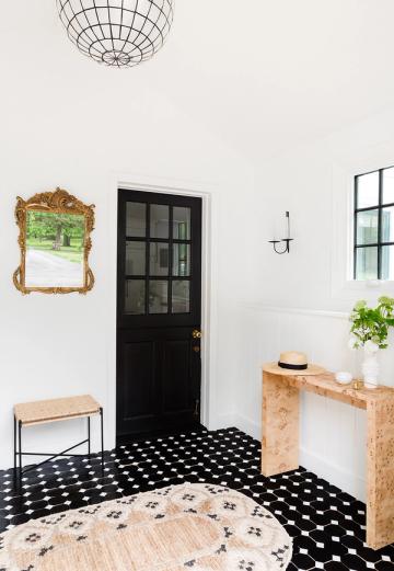 Modern farmhouse entryway with black accent door, geometric black tile flooring, and light wood console