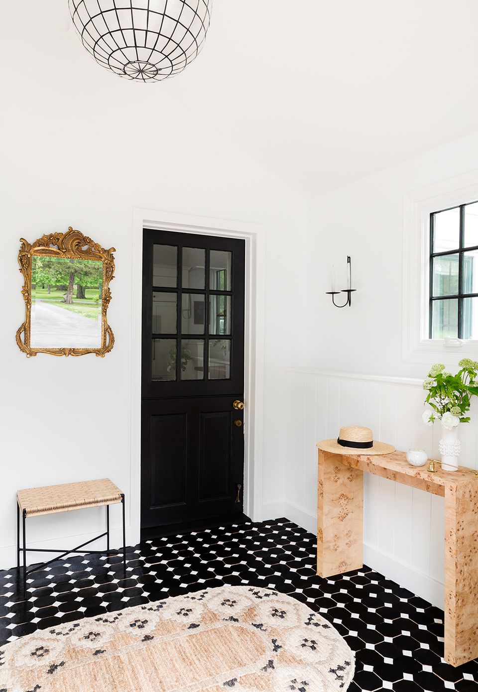 Modern farmhouse entryway with black accent door, geometric black tile flooring, and light wood console